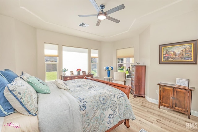 bedroom featuring ceiling fan, multiple windows, and light hardwood / wood-style flooring