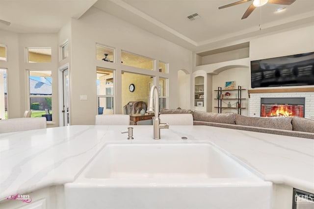 details featuring ceiling fan, a fireplace, and sink