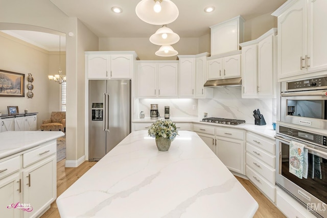 kitchen with stainless steel appliances, pendant lighting, white cabinets, and decorative backsplash