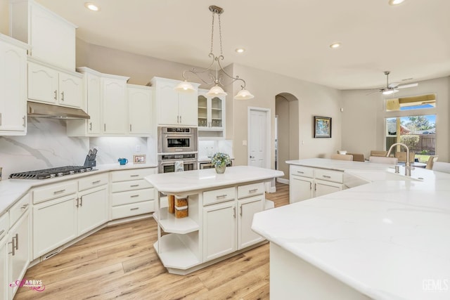 kitchen with sink, appliances with stainless steel finishes, hanging light fixtures, a center island, and white cabinets