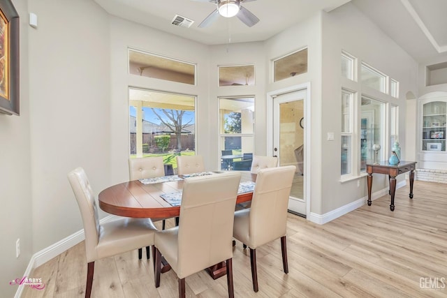 dining space with light hardwood / wood-style flooring, ceiling fan, and a high ceiling