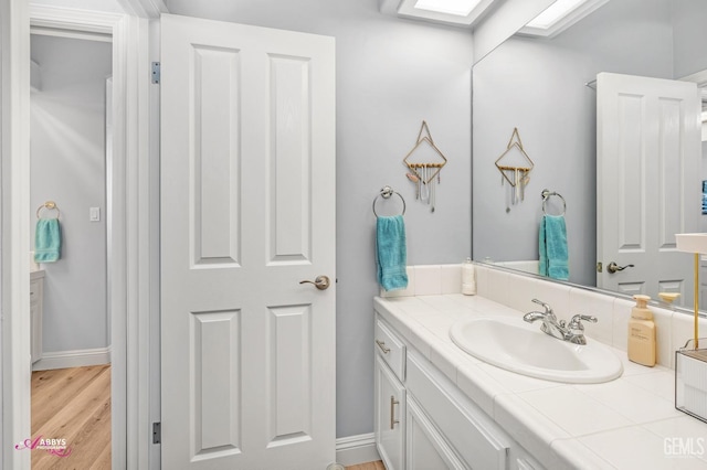 bathroom with vanity, wood-type flooring, and a skylight