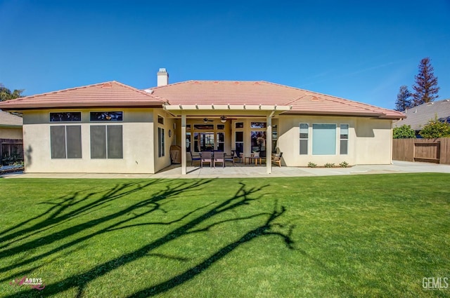 back of house featuring ceiling fan, a patio, and a lawn