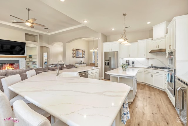 kitchen with sink, a breakfast bar, hanging light fixtures, stainless steel appliances, and an island with sink