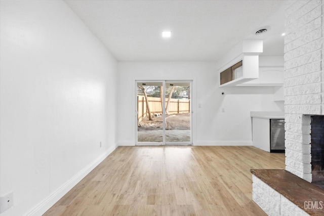 unfurnished living room featuring a fireplace and light hardwood / wood-style floors