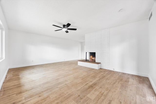 unfurnished living room featuring a brick fireplace, ceiling fan, and light hardwood / wood-style flooring