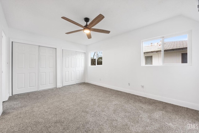 unfurnished bedroom featuring carpet floors, two closets, and ceiling fan