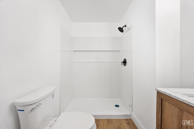 bathroom with vanity, wood-type flooring, toilet, and tiled shower