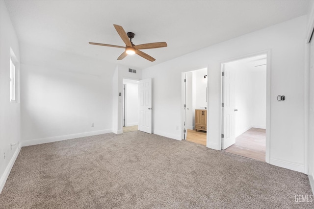 unfurnished bedroom with ensuite bathroom, light carpet, and ceiling fan