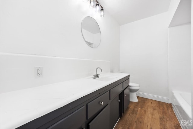 bathroom with vanity, a tub to relax in, hardwood / wood-style flooring, and toilet