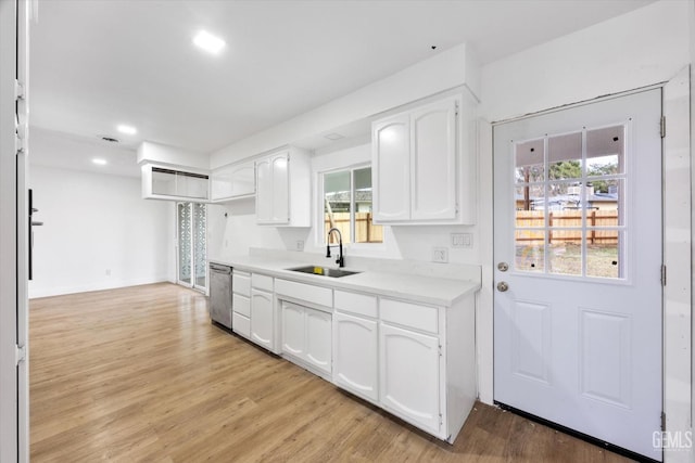 kitchen featuring white cabinetry, stainless steel dishwasher, sink, and light hardwood / wood-style flooring