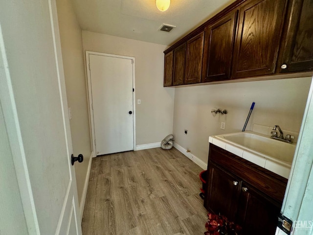 clothes washing area featuring hookup for a washing machine, cabinet space, visible vents, a sink, and light wood-type flooring