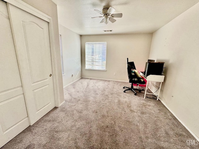 carpeted office space featuring visible vents, ceiling fan, a textured ceiling, and baseboards