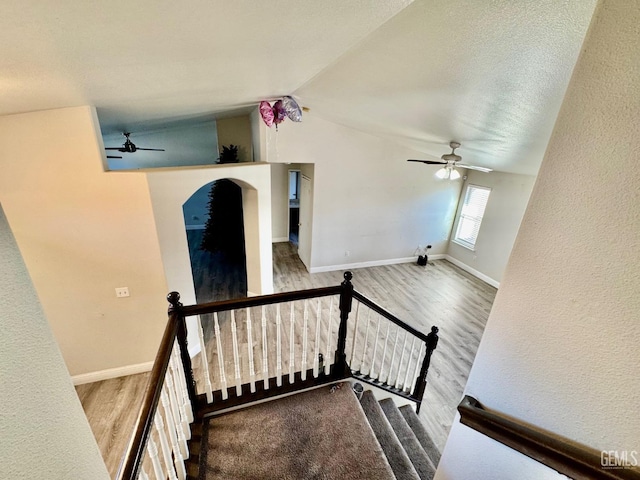 stairway featuring vaulted ceiling, wood finished floors, and baseboards