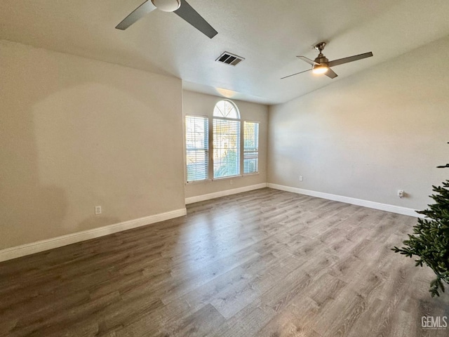 unfurnished room with wood finished floors, visible vents, and baseboards