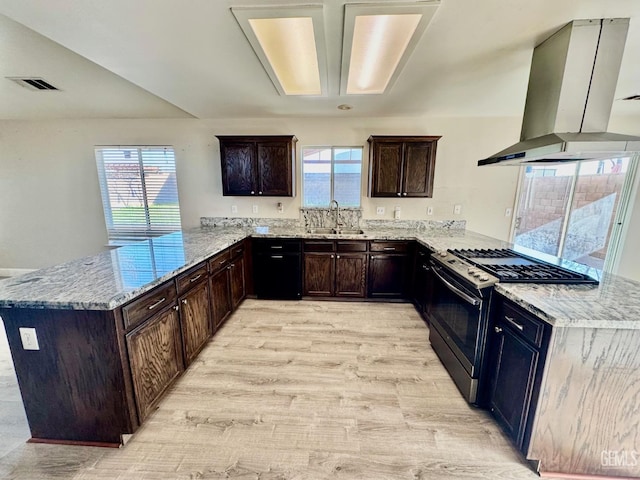 kitchen featuring visible vents, stainless steel range with gas stovetop, a peninsula, island exhaust hood, and a sink