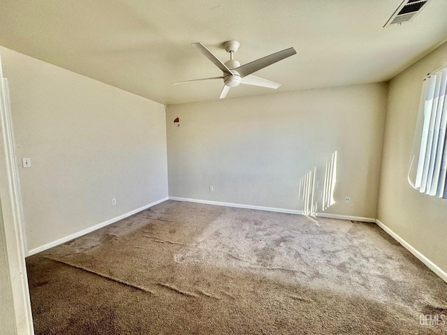 carpeted spare room featuring baseboards, visible vents, and ceiling fan