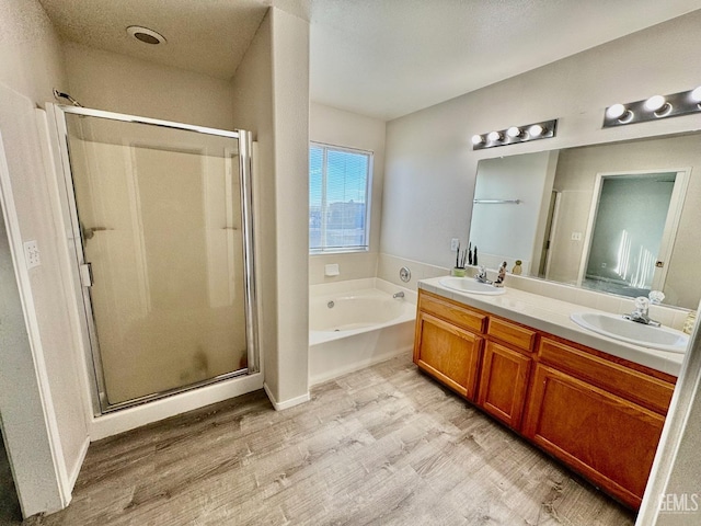 bathroom with a garden tub, wood finished floors, a sink, and a shower stall