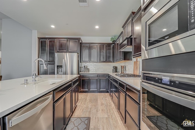 kitchen featuring sink, light hardwood / wood-style flooring, dark brown cabinets, and appliances with stainless steel finishes