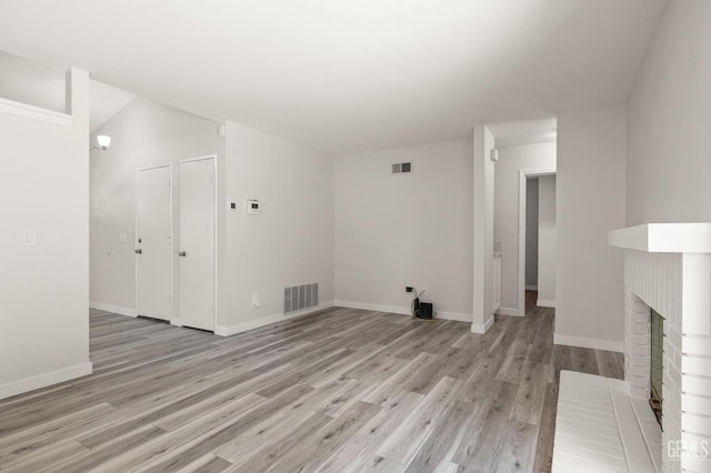 unfurnished living room featuring visible vents, a fireplace, and light wood-style flooring