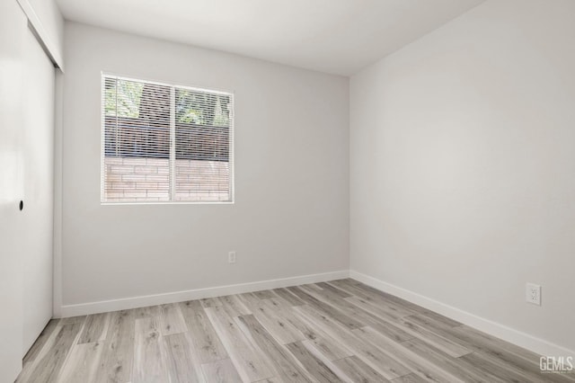 spare room featuring light wood-type flooring and baseboards