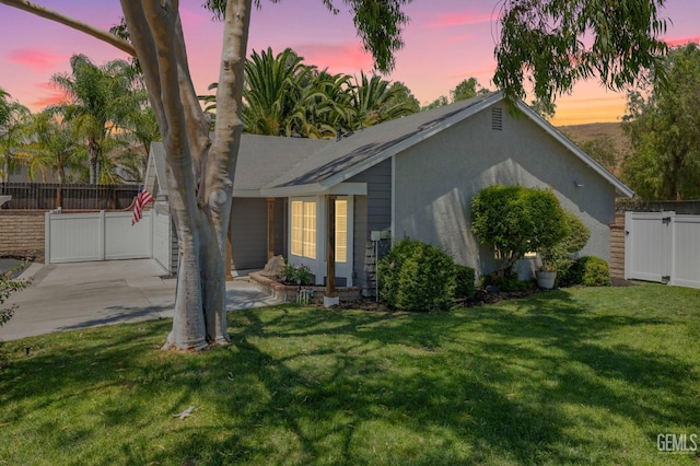 ranch-style house with a yard, fence, and driveway