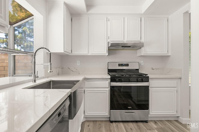 kitchen featuring light stone counters, stainless steel range with gas cooktop, white cabinets, and under cabinet range hood