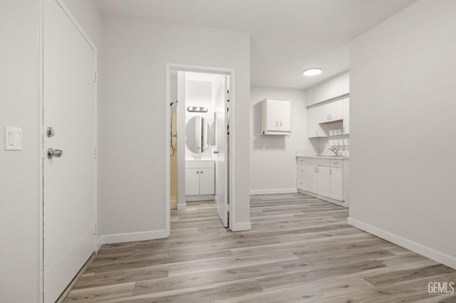 hallway with light wood-type flooring and baseboards