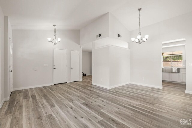 interior space featuring high vaulted ceiling, light wood-style flooring, visible vents, and a notable chandelier