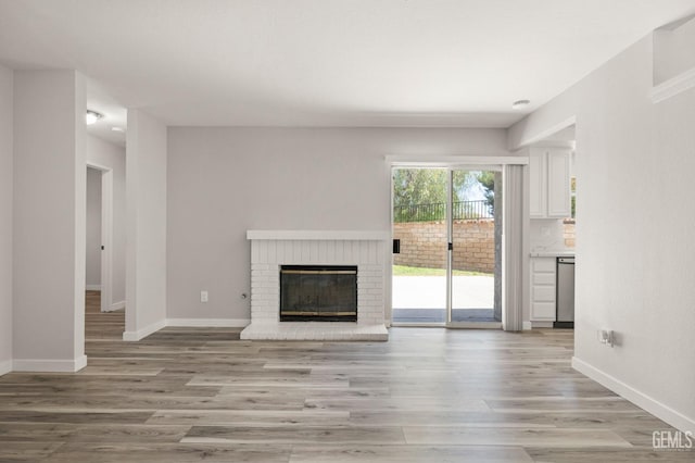 unfurnished living room with a fireplace, light wood-style flooring, and baseboards