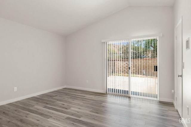 empty room with baseboards, vaulted ceiling, and wood finished floors