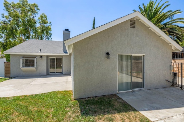 back of house with a patio area, fence, a chimney, and stucco siding