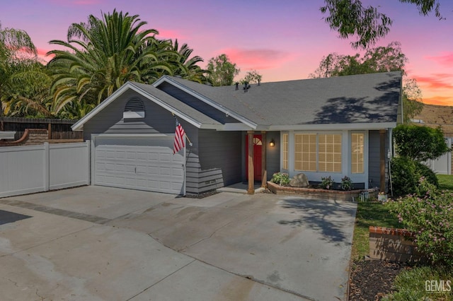 view of front of property featuring an attached garage, driveway, and fence