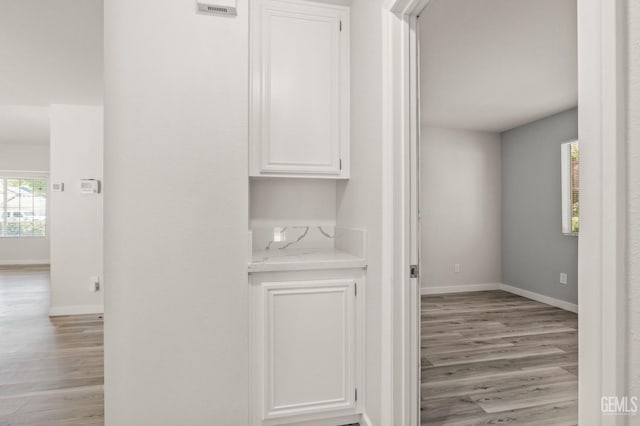 hallway with baseboards, plenty of natural light, and light wood finished floors