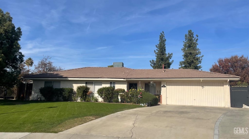 ranch-style home with driveway, an attached garage, and a front yard