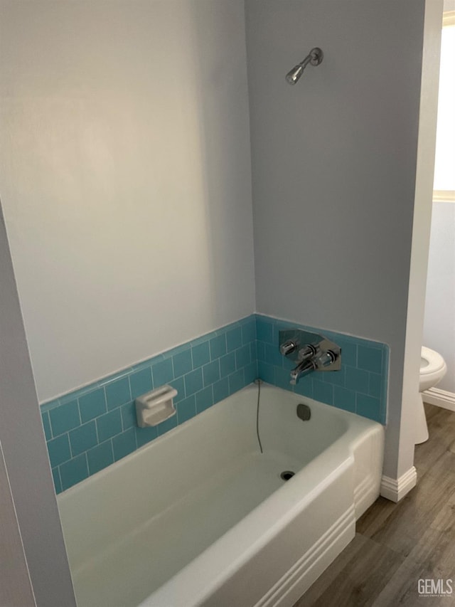 bathroom featuring hardwood / wood-style flooring, toilet, and a bath