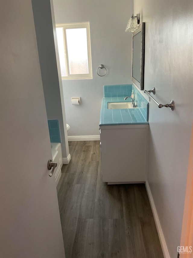 bathroom with hardwood / wood-style flooring, vanity, and toilet