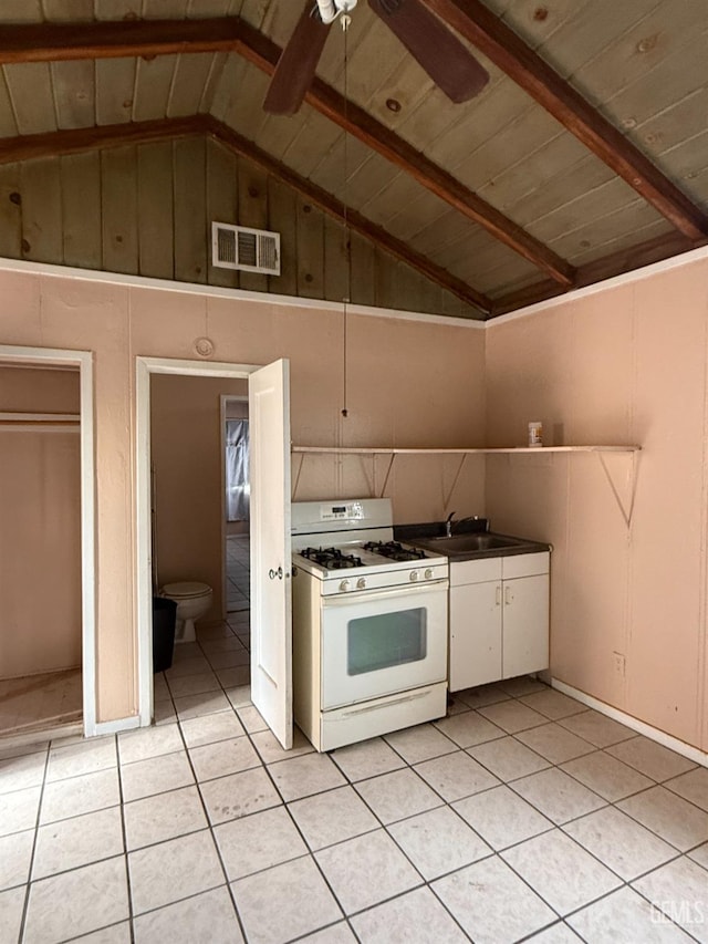 kitchen featuring ceiling fan, lofted ceiling with beams, sink, white range with gas stovetop, and light tile patterned floors