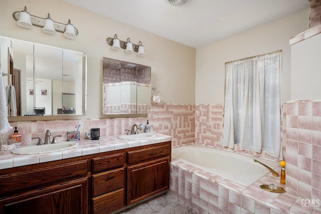 bathroom with a relaxing tiled tub, tile patterned floors, and vanity