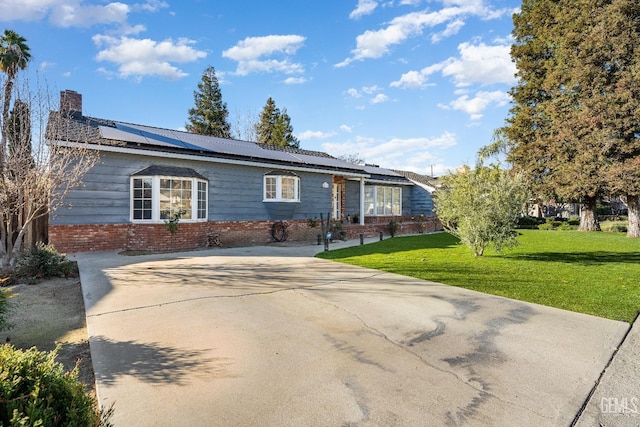 single story home featuring solar panels and a front lawn