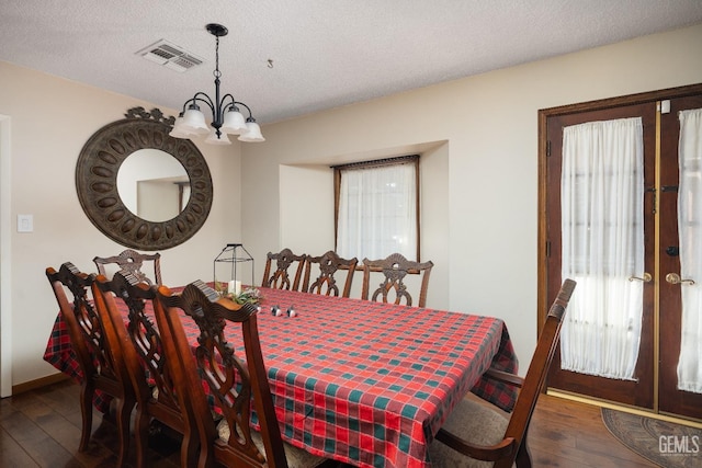 dining space featuring french doors, dark hardwood / wood-style flooring, a textured ceiling, and a chandelier