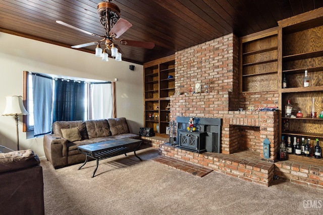 living room with ceiling fan, built in shelves, a wood stove, and carpet flooring