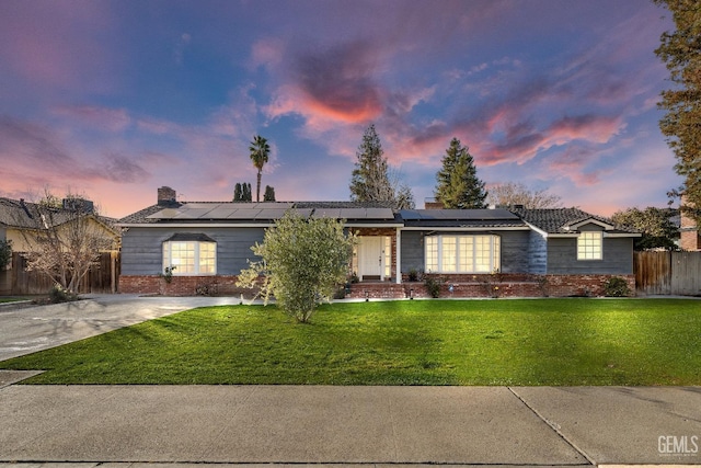 single story home featuring solar panels and a yard