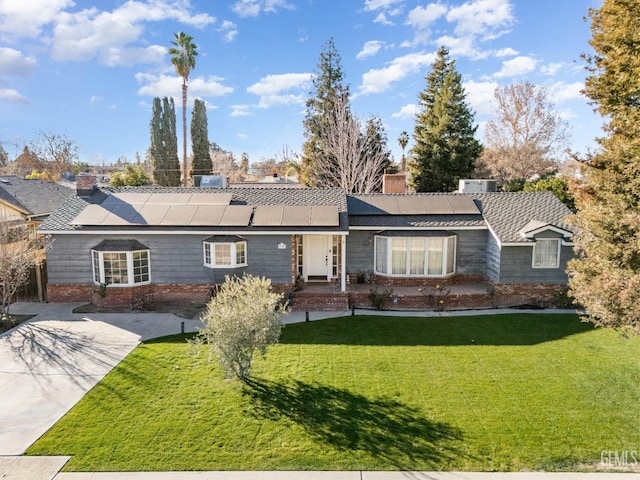 ranch-style home with solar panels and a front lawn