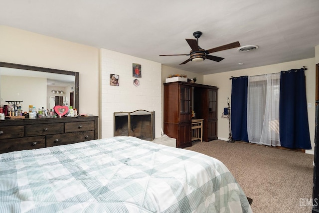 bedroom featuring carpet flooring, a brick fireplace, and ceiling fan