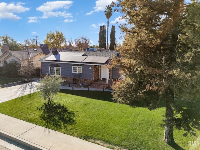 view of front of property featuring solar panels and a front lawn