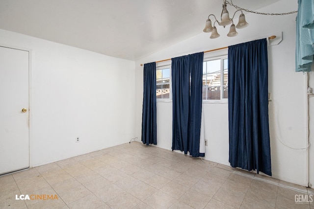 spare room featuring lofted ceiling and an inviting chandelier