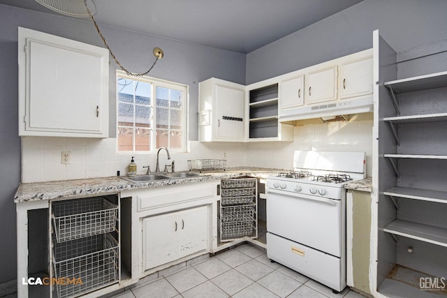 kitchen with sink, white gas stove, white cabinetry, light tile patterned floors, and backsplash