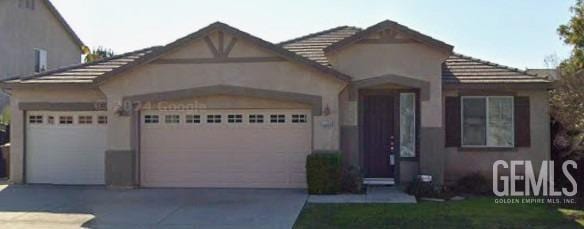 view of front of house with stucco siding, driveway, an attached garage, and a tiled roof