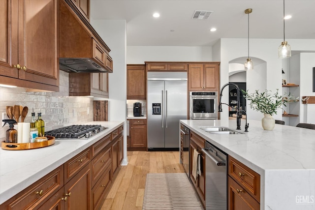 kitchen with a sink, pendant lighting, light wood finished floors, appliances with stainless steel finishes, and visible vents